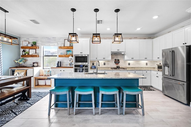 kitchen featuring appliances with stainless steel finishes, a kitchen island with sink, white cabinetry, pendant lighting, and a sink