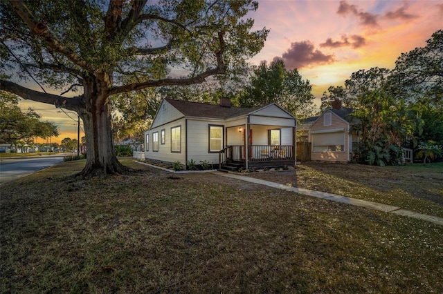 view of front of home with covered porch and a yard