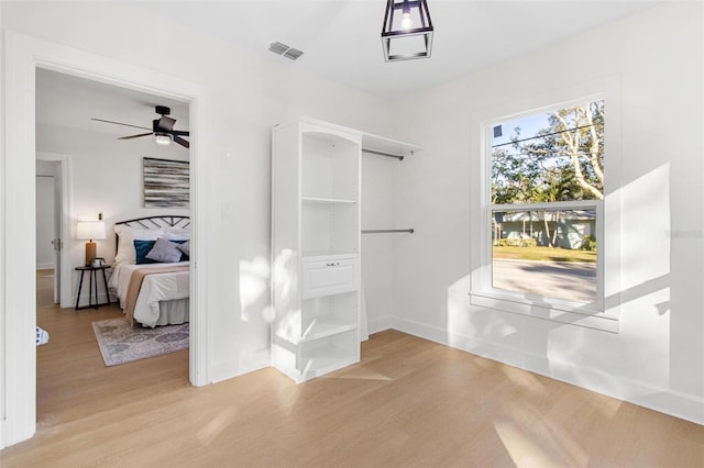 walk in closet featuring light wood-type flooring and ceiling fan