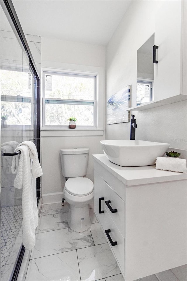 bathroom with vanity, toilet, an enclosed shower, and a healthy amount of sunlight