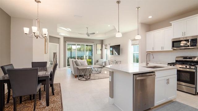 kitchen featuring sink, white cabinets, stainless steel appliances, and ceiling fan with notable chandelier