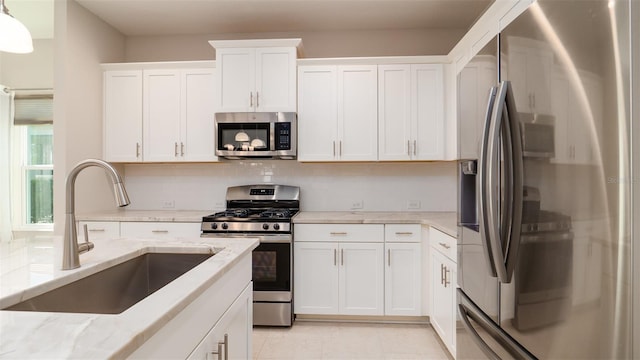 4326 Tamarind Pl, Bradenton, FL 34203 - kitchen with stainless steel appliances, a sink, white cabinets, light stone counters, and backsplash
