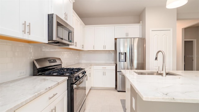 kitchen featuring backsplash, white cabinets, sink, light stone countertops, and appliances with stainless steel finishes