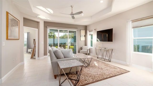 tiled living room with a raised ceiling and ceiling fan