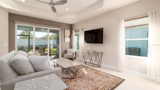 living room with a tray ceiling and ceiling fan