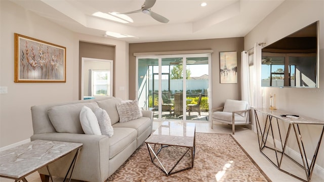 tiled living room with ceiling fan and a raised ceiling