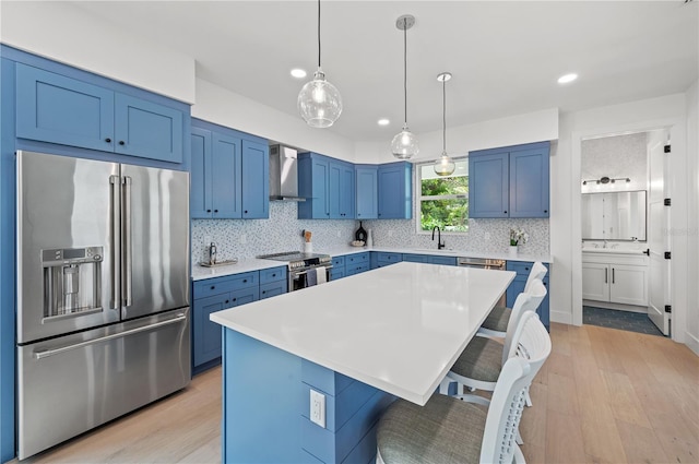 kitchen featuring a kitchen bar, light wood-type flooring, stainless steel appliances, wall chimney range hood, and a center island