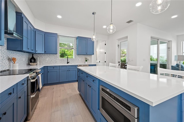 kitchen featuring decorative backsplash, appliances with stainless steel finishes, a center island, and light hardwood / wood-style floors