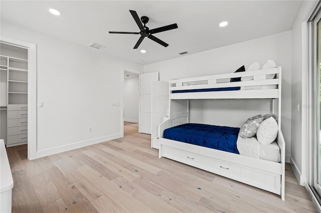 unfurnished bedroom featuring a closet, light hardwood / wood-style floors, a spacious closet, and ceiling fan