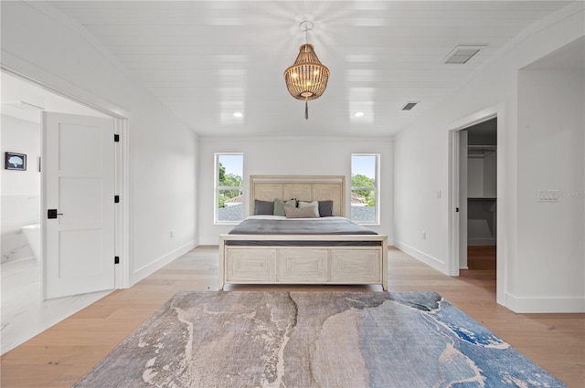 bedroom with ensuite bath, a closet, light hardwood / wood-style flooring, and a spacious closet