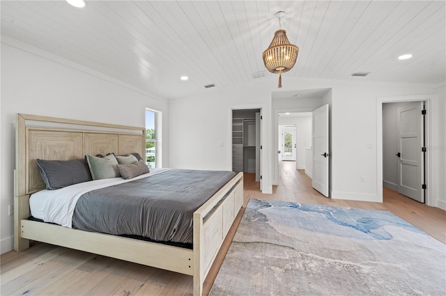 bedroom with wood ceiling, a walk in closet, and light hardwood / wood-style floors