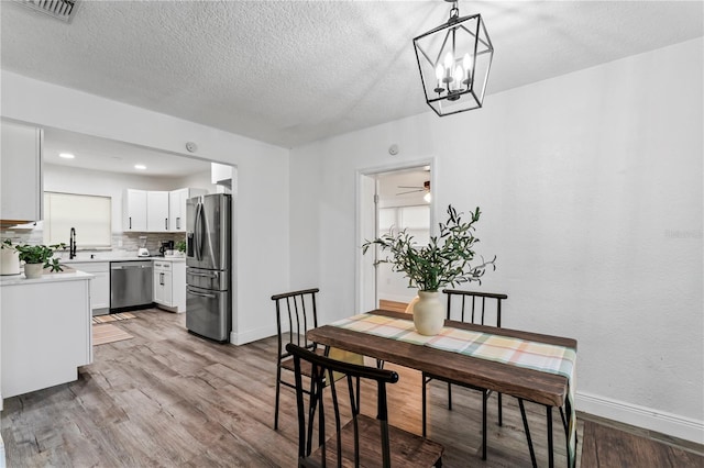 dining space featuring a chandelier, a textured ceiling, light hardwood / wood-style floors, and sink