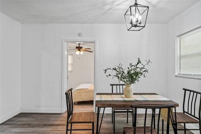 dining area featuring dark hardwood / wood-style floors, a textured ceiling, and ceiling fan with notable chandelier