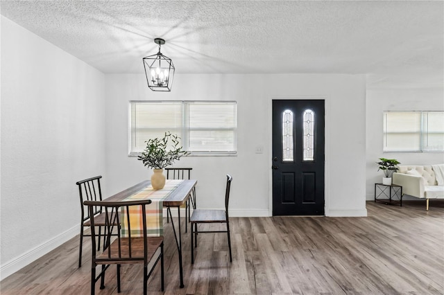 dining room featuring hardwood / wood-style floors, a textured ceiling, and a chandelier