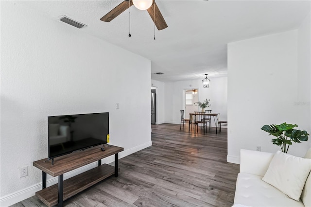 living room with dark hardwood / wood-style flooring and ceiling fan with notable chandelier