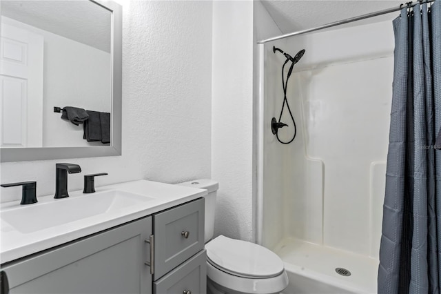 bathroom with vanity, curtained shower, toilet, and a textured ceiling