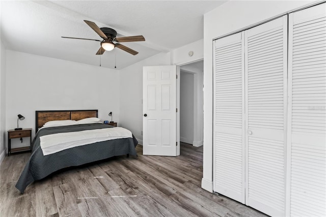 bedroom featuring a closet, hardwood / wood-style flooring, vaulted ceiling, and ceiling fan