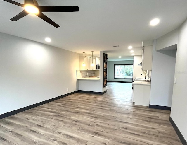 unfurnished living room featuring ceiling fan, light hardwood / wood-style flooring, and sink