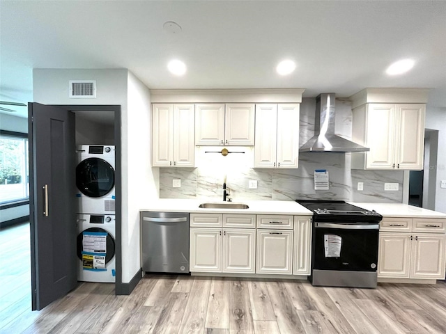 kitchen featuring appliances with stainless steel finishes, light wood-type flooring, wall chimney exhaust hood, and sink