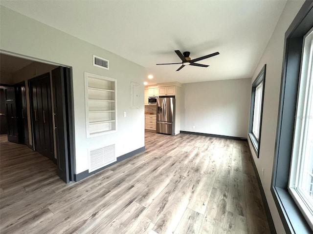 unfurnished room featuring built in shelves, ceiling fan, and light hardwood / wood-style flooring