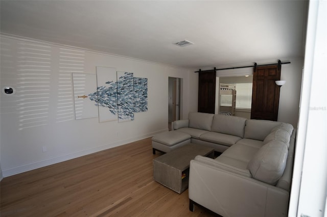 living room with hardwood / wood-style flooring, a barn door, and crown molding