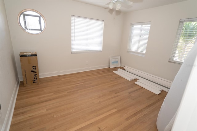 spare room with a wealth of natural light, light hardwood / wood-style flooring, ceiling fan, and a baseboard radiator