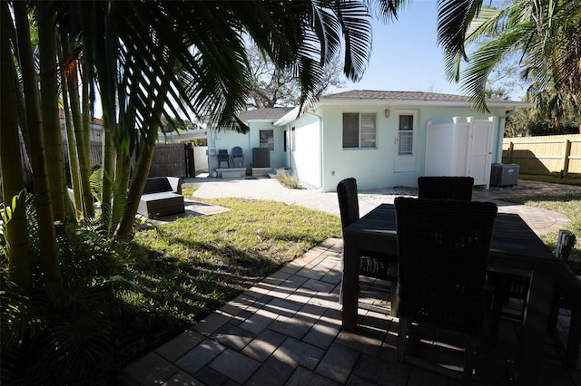 exterior space with central AC, a patio area, and a lawn