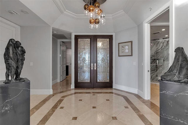 foyer entrance with french doors, crown molding, a raised ceiling, and a notable chandelier