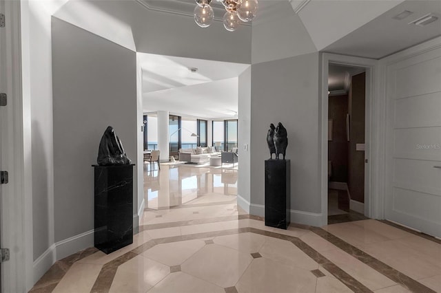 tiled entrance foyer featuring crown molding and an inviting chandelier