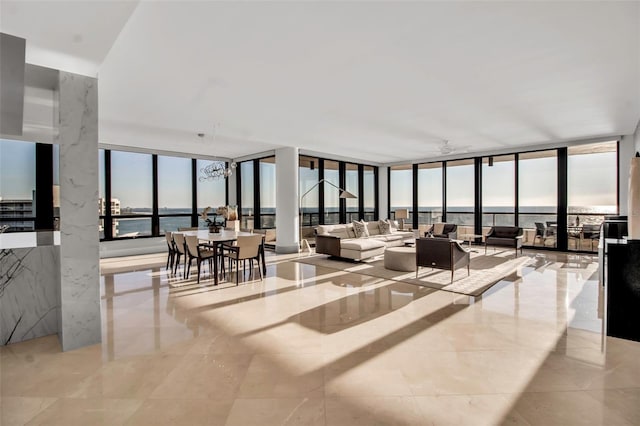 living room featuring ceiling fan, a water view, a wall of windows, and light tile patterned floors