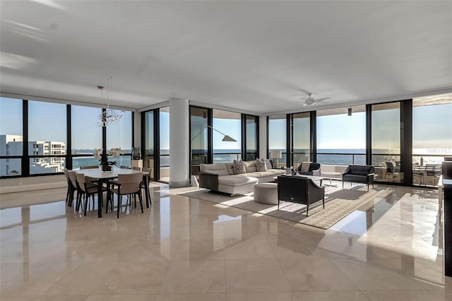 living room featuring a water view, a wealth of natural light, expansive windows, and ceiling fan with notable chandelier