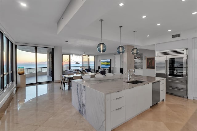 kitchen with stainless steel appliances, white cabinetry, a large island, and light stone counters