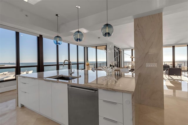 kitchen with a kitchen island with sink, a water view, sink, decorative light fixtures, and white cabinetry