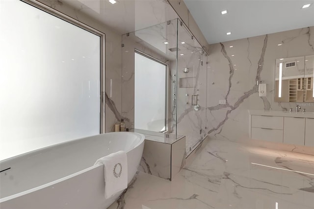 bathroom with separate shower and tub, vanity, and tile walls