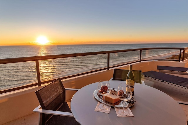 balcony at dusk featuring a water view