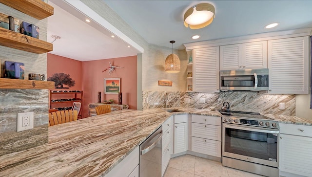 kitchen with kitchen peninsula, pendant lighting, white cabinets, and stainless steel appliances