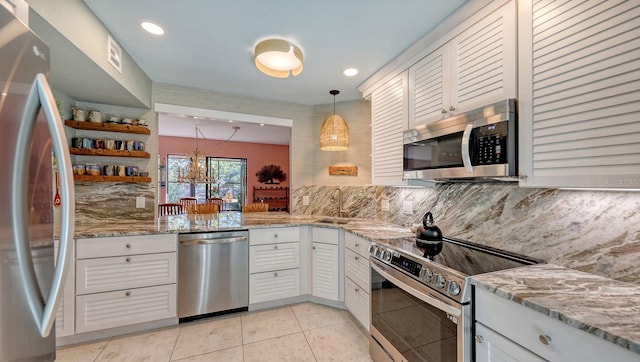 kitchen featuring hanging light fixtures, backsplash, a chandelier, white cabinets, and appliances with stainless steel finishes