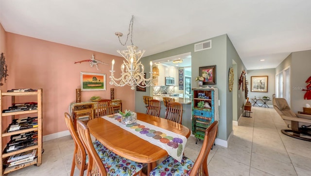 dining space with light tile patterned floors and an inviting chandelier