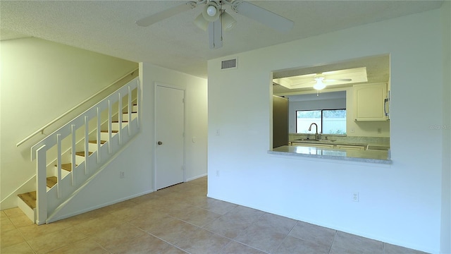 empty room featuring ceiling fan, sink, and a textured ceiling