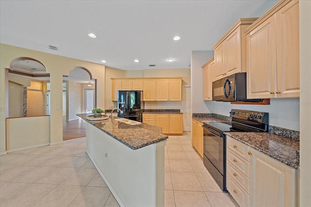 kitchen with a center island with sink, black appliances, sink, light tile patterned floors, and light brown cabinetry