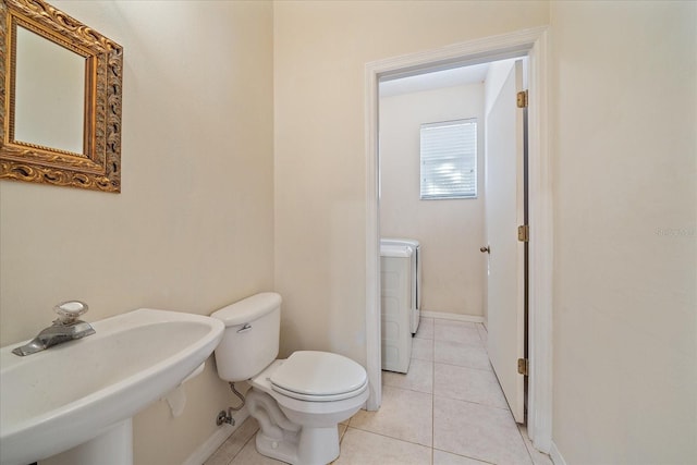 bathroom with toilet, tile patterned flooring, washer / dryer, and sink