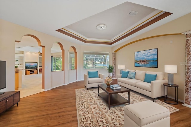 living room with ceiling fan, hardwood / wood-style floors, ornamental molding, and a raised ceiling