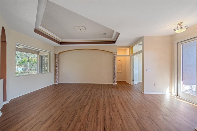 unfurnished living room featuring hardwood / wood-style floors, ornamental molding, and a raised ceiling