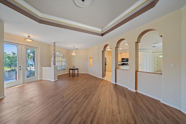 spare room featuring hardwood / wood-style flooring, a raised ceiling, ornamental molding, and french doors