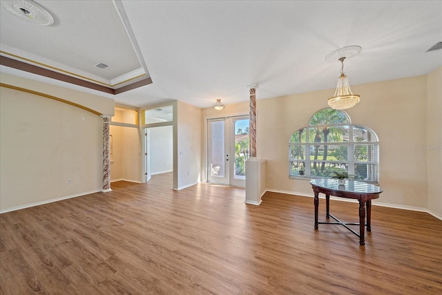 interior space with hardwood / wood-style flooring, a raised ceiling, crown molding, and french doors