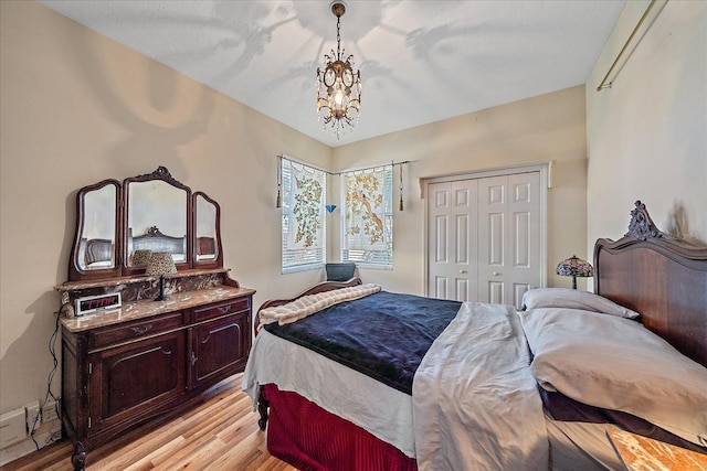 bedroom with a closet, a chandelier, and light hardwood / wood-style flooring