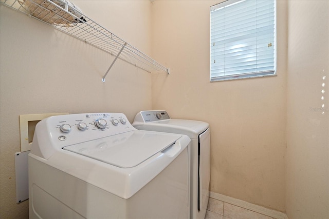 laundry area with washer and clothes dryer and light tile patterned floors