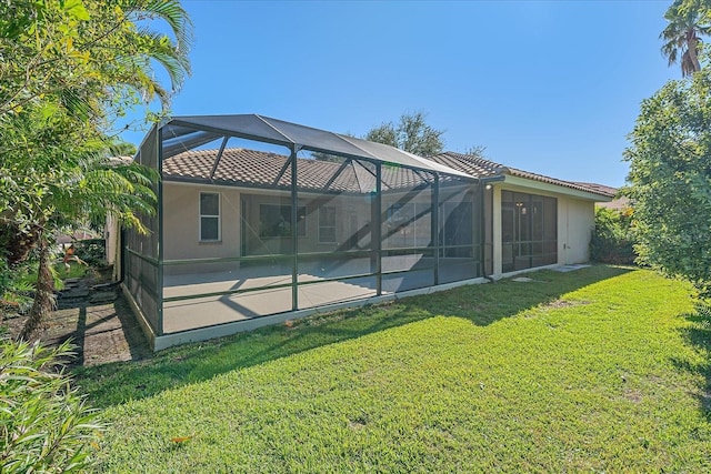 rear view of property featuring a yard and glass enclosure