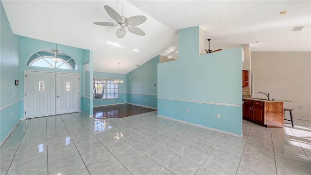 foyer featuring sink, light tile patterned floors, ceiling fan with notable chandelier, and high vaulted ceiling