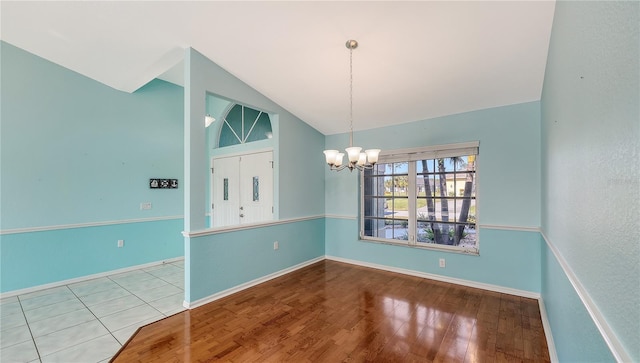 unfurnished dining area featuring wood-type flooring, lofted ceiling, and a notable chandelier